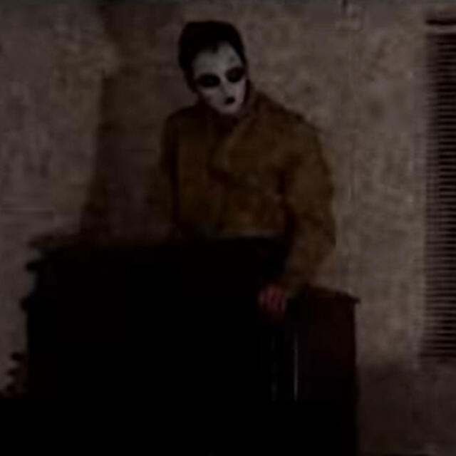 a screenshot of masky from marble hornets sitting on a dresser